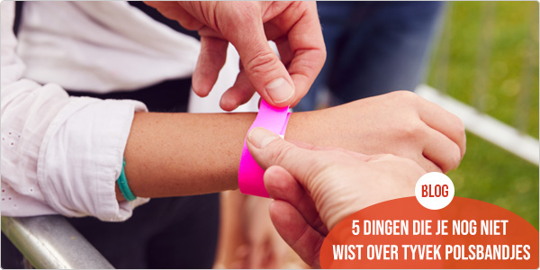 iemand brengt een roze tyvek polsbandjes aan bij een bezoeker van een outdoor event