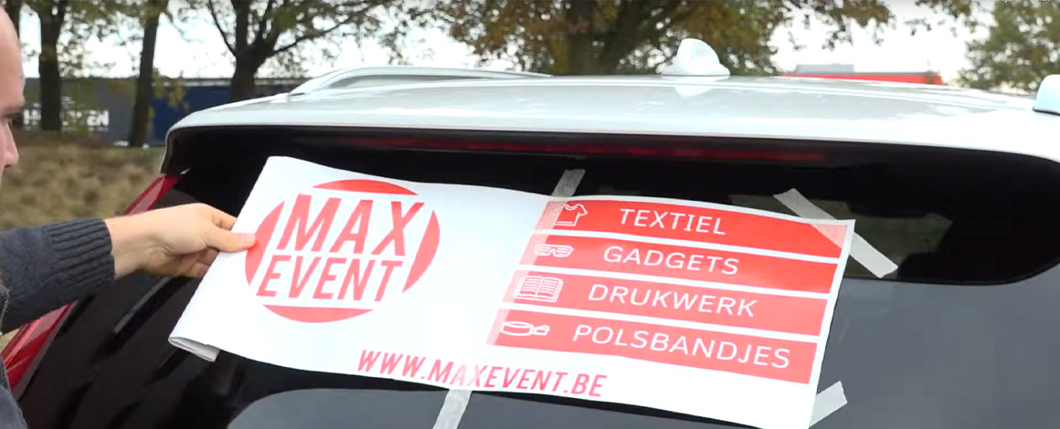autosticker met reclame voor firma wordt bevestigd op een witte auto