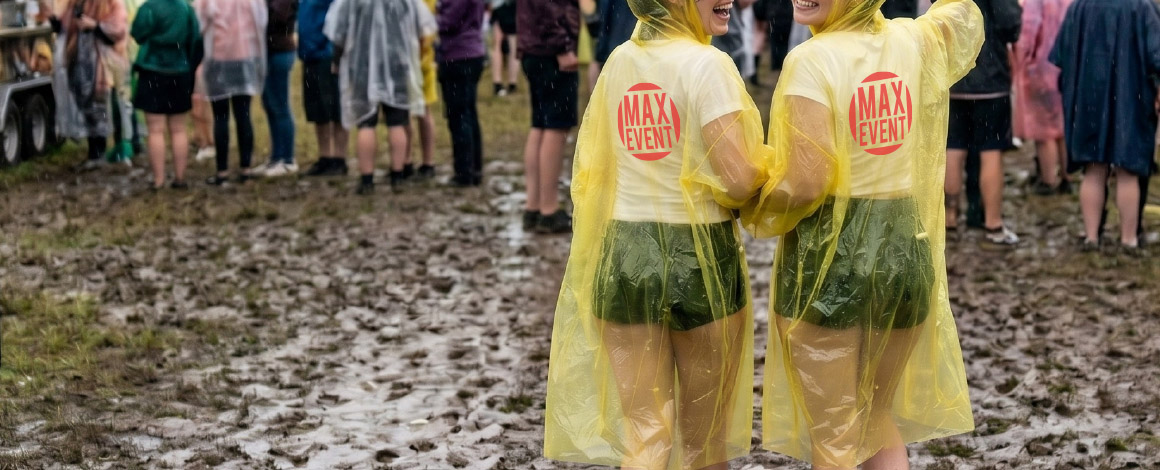 2 dames lopen een ondergeregend festival terrein in een bedrukte gele poncho